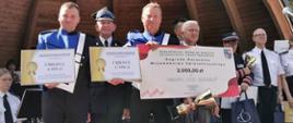 Tryumfatorzy z nagrodami. W rękach trzymają symboliczne czeki za wygranie rywalizacji.