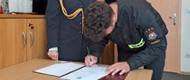 Strażak 1 podpisujący akt ślubowania 
