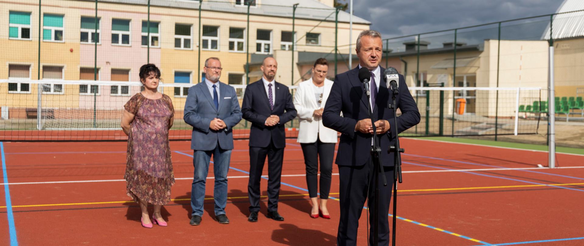 
Grupa ludzi w garniturach stojąca na boisku sportowym
