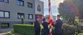 Poczet flagowy w liczbie 3 strażaków dokonuje podniesienia flagi państwowej na maszcie przed budynkiem komendy