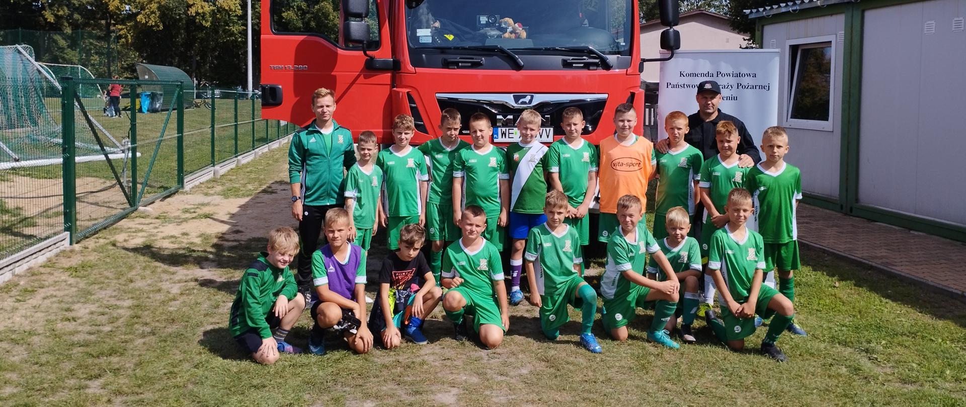 Drużyna piłkarska młodzików przed samochodem pożarniczym