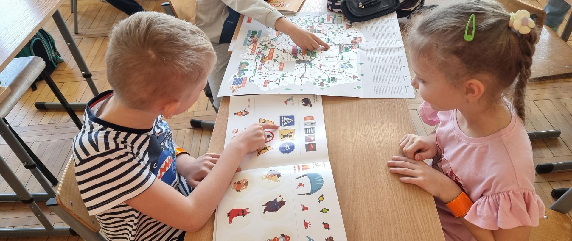 Lekcja edukacyjna - dzieci oglądają książeczkę ze znakami drogowymi 