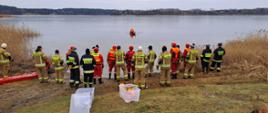 Zdjęcie przedstawia strażaków PSP i OSP w tle jezioro Głuszyńskie podczas ćwiczeń z zakresu ratownictwa lodowego.