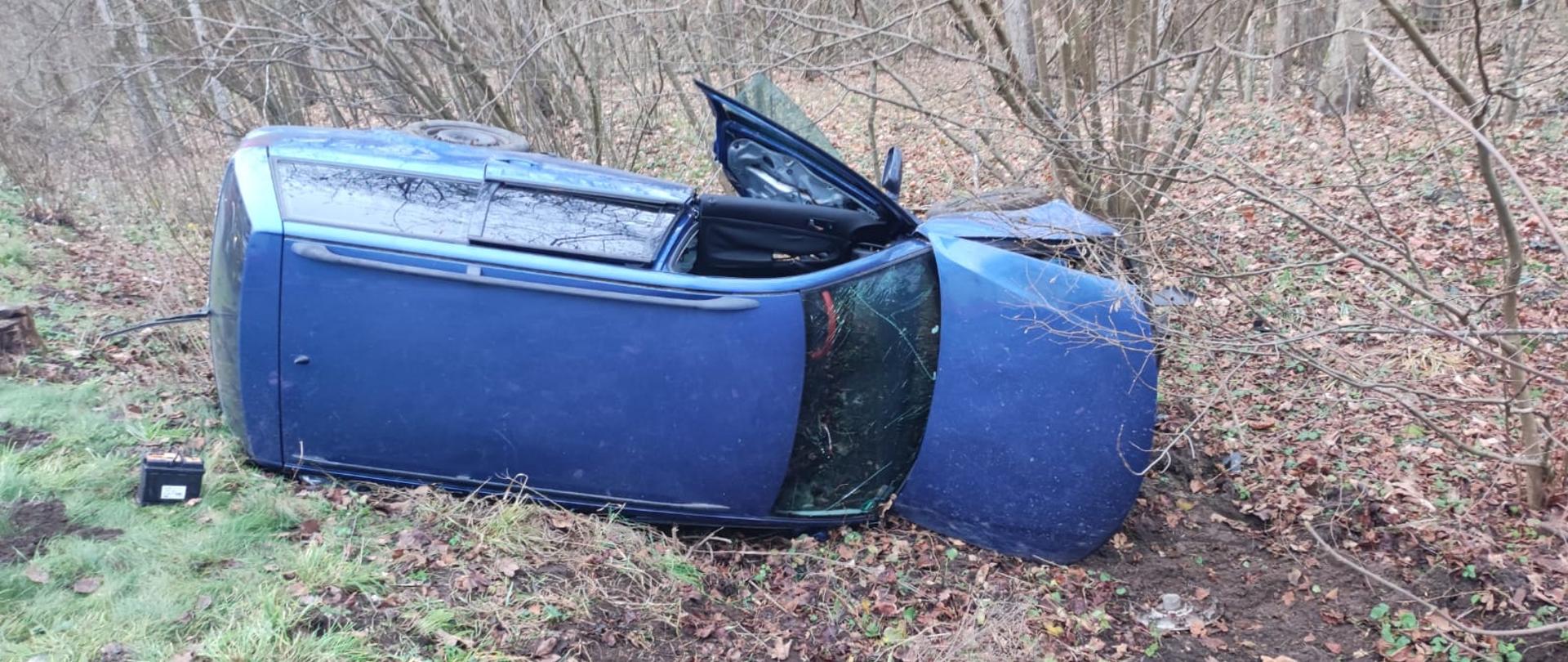 Zdjęcie przedstawia niebieskiego passata komi rozbitego w rowie.