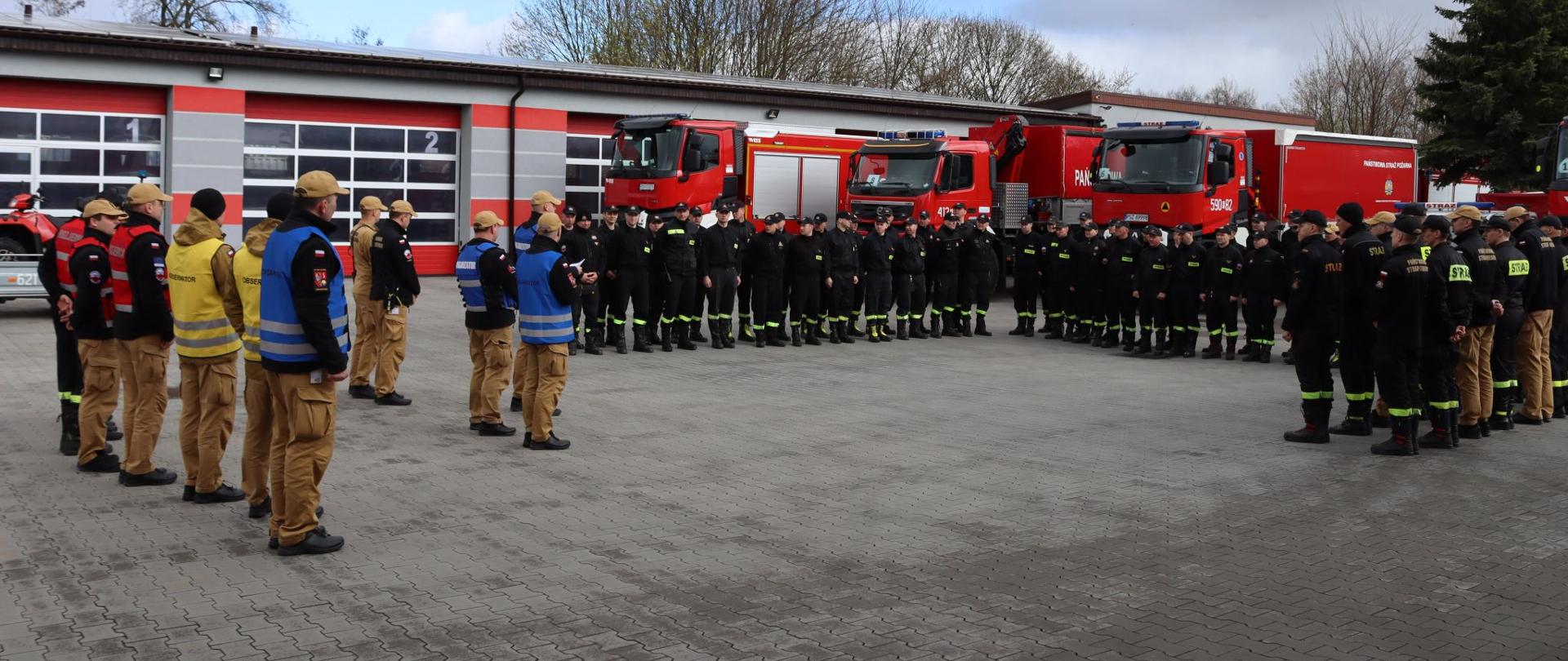 Zbiórka przed ćwiczeniami na placu komendy, w tle samochody pożarnicze