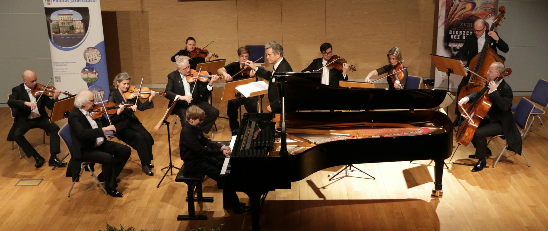 Zdjęcie Orkiestry Kameralnej Filharmonii Narodowej podczas koncertu na scenie wraz z pianistą (przy fortepianie Mateusz Łuczak fot. Starostwo Powiatowe w Jarosławiu
