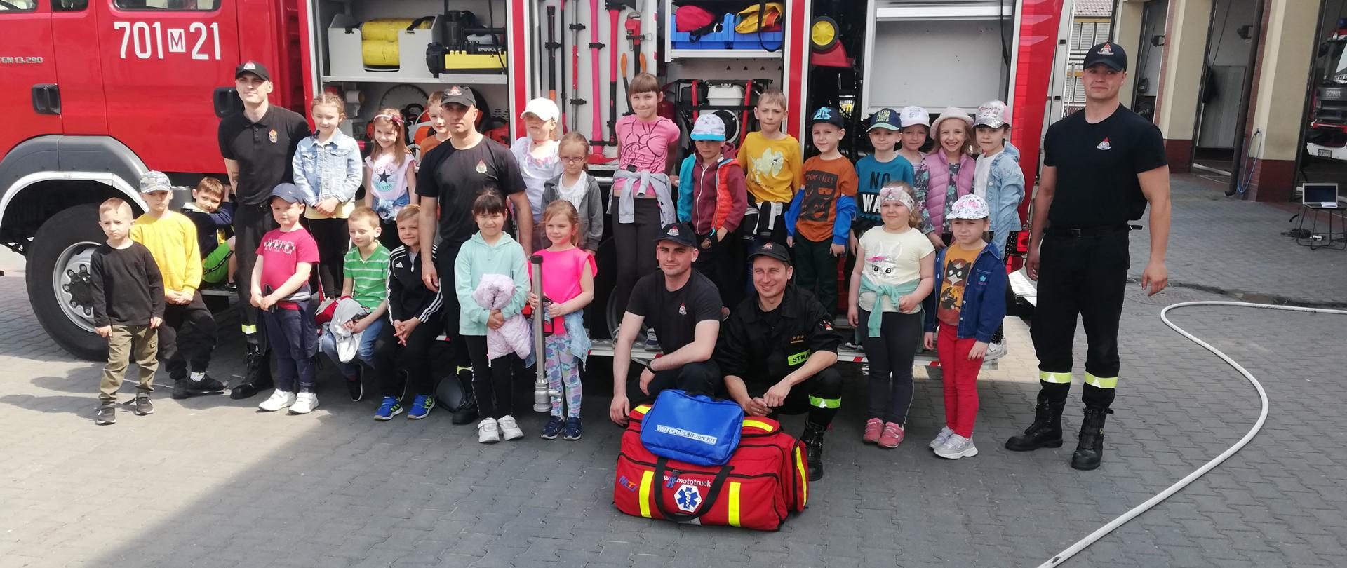 Zdjęcie grupowe dzieci ze strażakami obok samochodu pożarniczego
