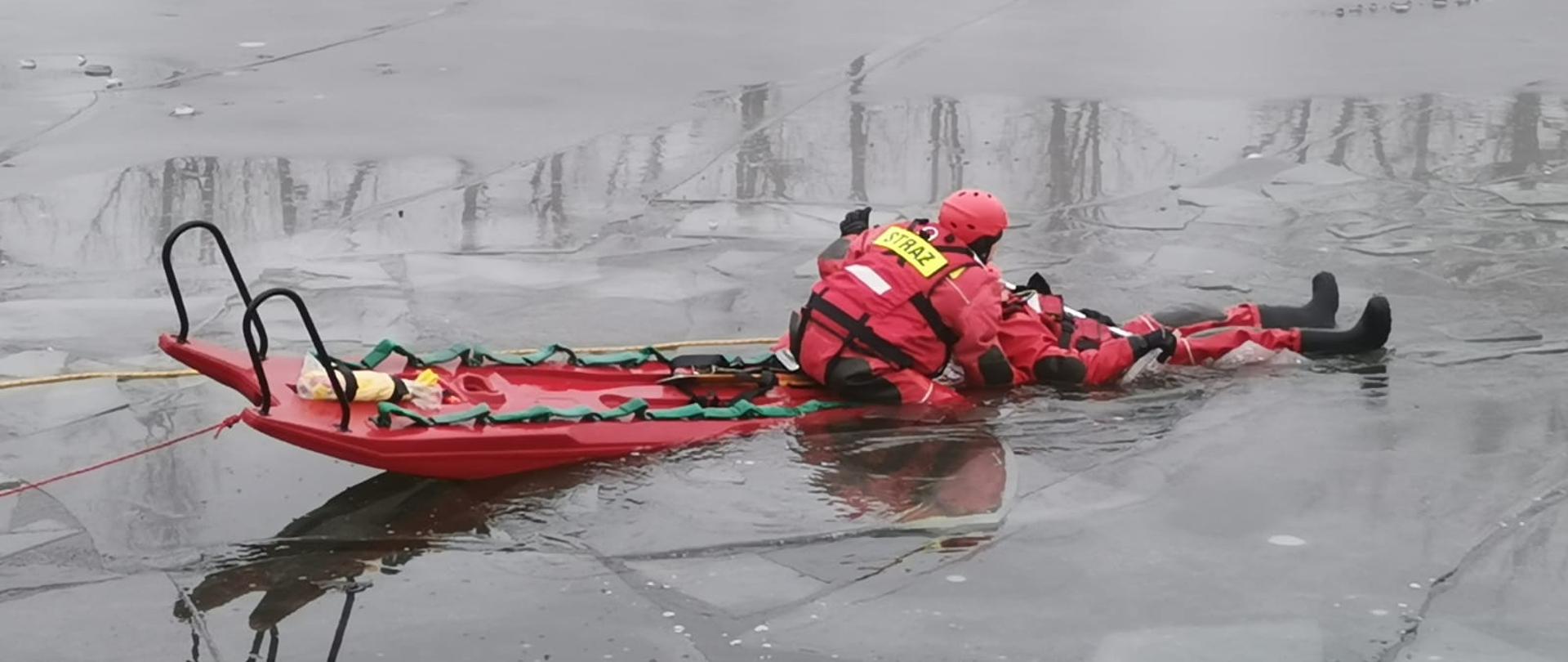 Ratownik podbiera osobę z pękniętego lodu na sanie wodno-lodowe