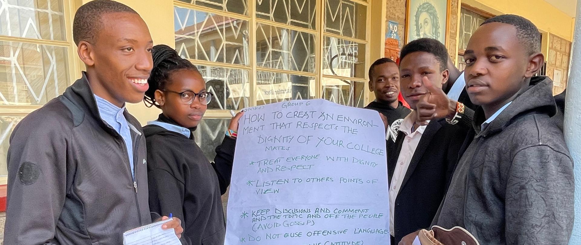 Przed budynkiem szkoły grupa uczniów trzyma w arkusz papieru z notatkami