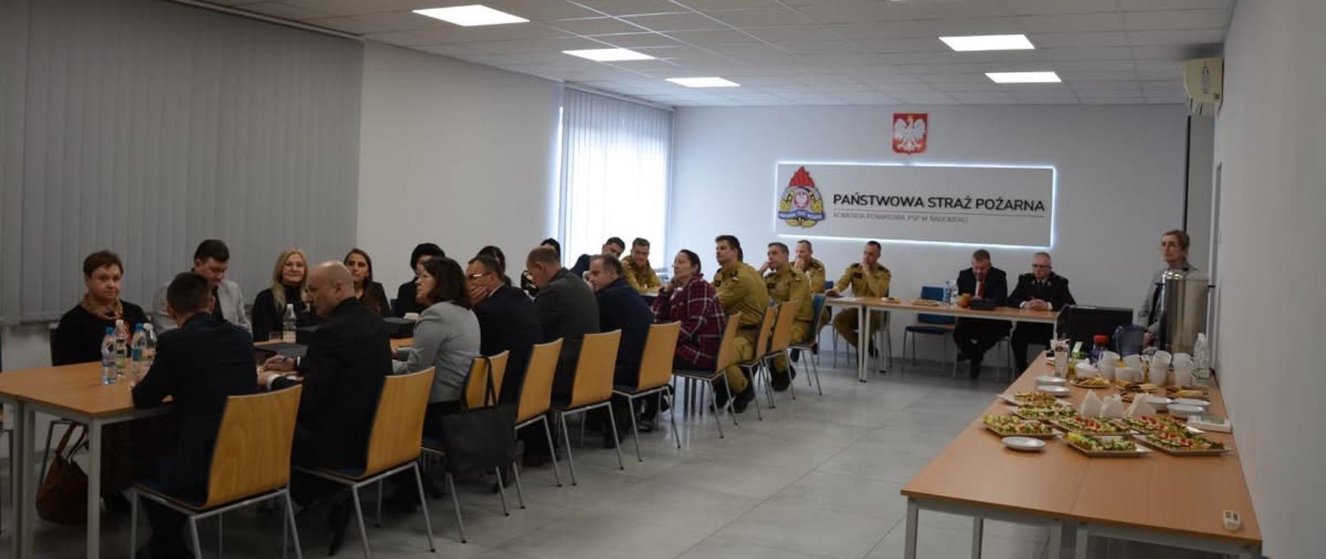 Przy stole siedzący zaproszeni goście.