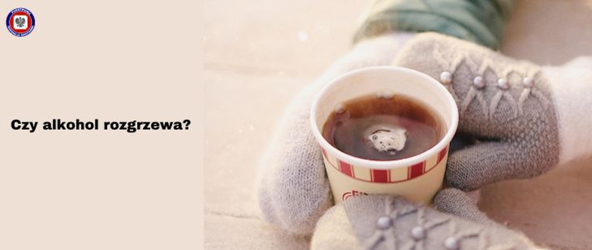 Po prawej dłonie w rękawiczkach trzymające napój w papierowym kubku. Po lewej na beżowym tle czarny napis Czy alkohol rozgrzewa? W lewym górnym rogu logo Państwowej Inspekcji Sanitarnej. 