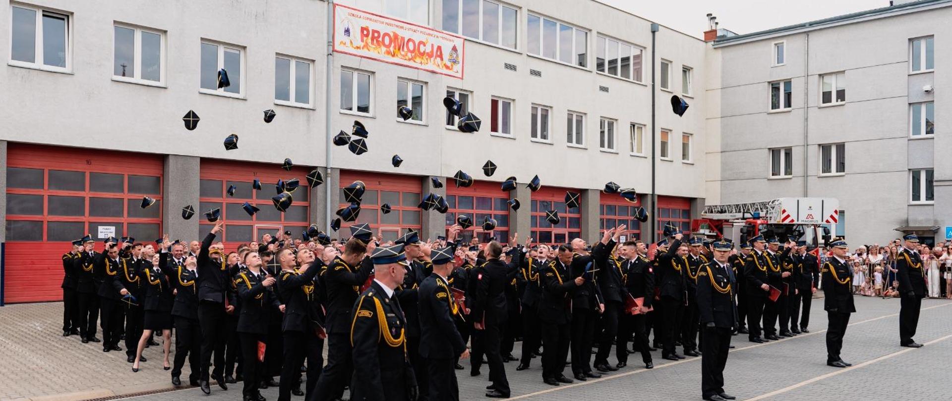 Absolwenci podrzucają rogatywki w powietrze. 