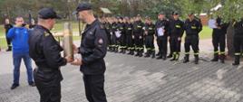 Na zdjęciu są trzy drużyny strażaków, które odebrały puchary oraz dyplomy za najlepsze wyniki w strzelectwie, w kategorii dwubój. W tle widać wigwam oraz banery z nazwami powiatu grodzisk wielkopolski. 