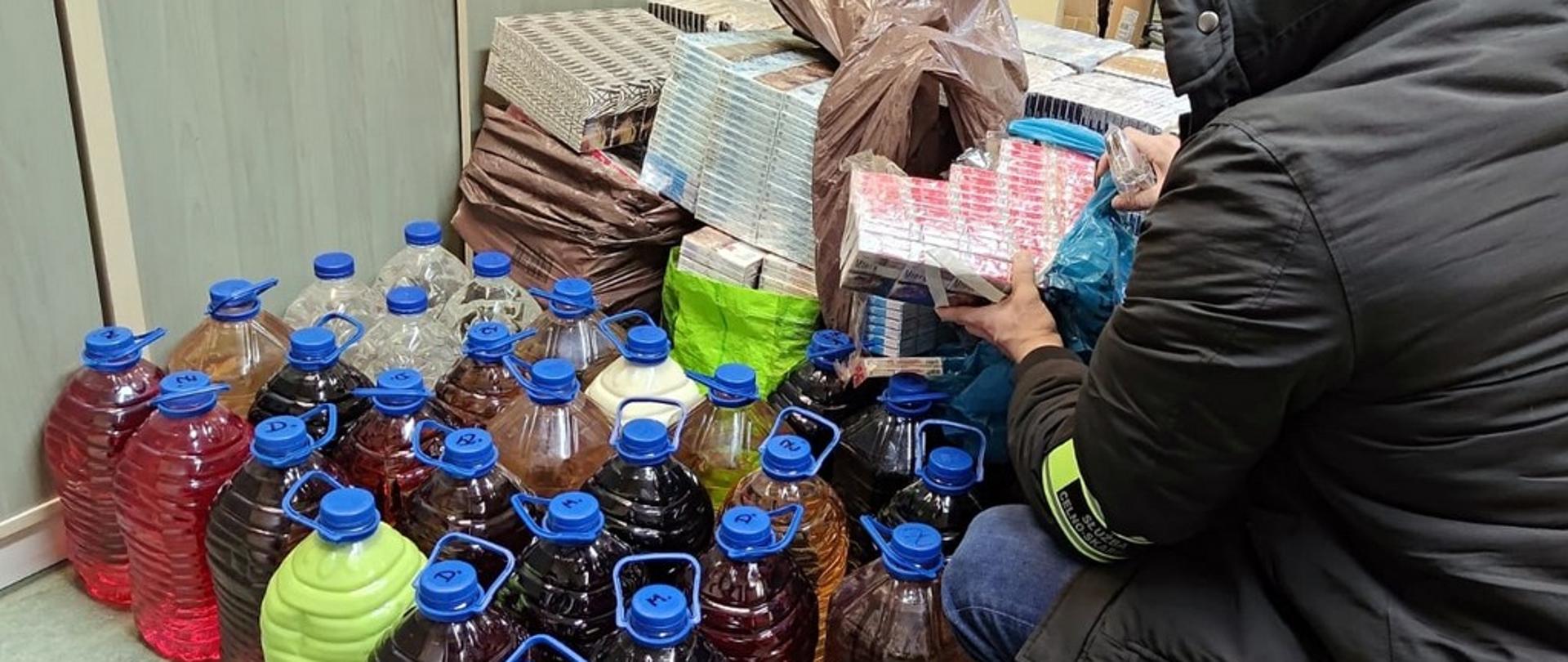 Funkcjonariusz przy zabezpieczonych papierosach i alkoholu
