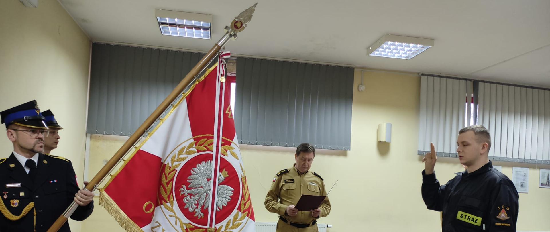 str. Daniel Lepianka składa ślubowanie przed sztandarem KP PSP w Grodzisku Mazowieckim w obecności Komendanta Powiatowego PSP w Grodzisku Mazowieckim st. bryg. Krzysztofa Tryniszewskiego. 