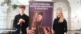 na zdjęciu na tle fioletowego baneru z białymi napisami ogólnopolski konkurs fagotowy stoją dwie postacie kobieta w blond włosach czarnym swetrze i kolorowej spódnicy