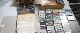 Archiwalne dokumenty, kasety magnetofonowe i wideo na stole.