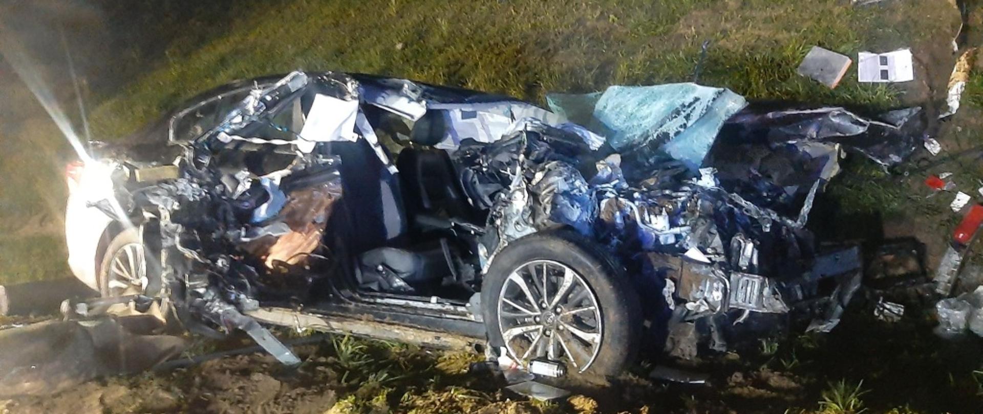 Na zdjęciu widoczny jest samochód osobowy stojący w przydrożnym rowie, auto jest całkowicieuszkodzone