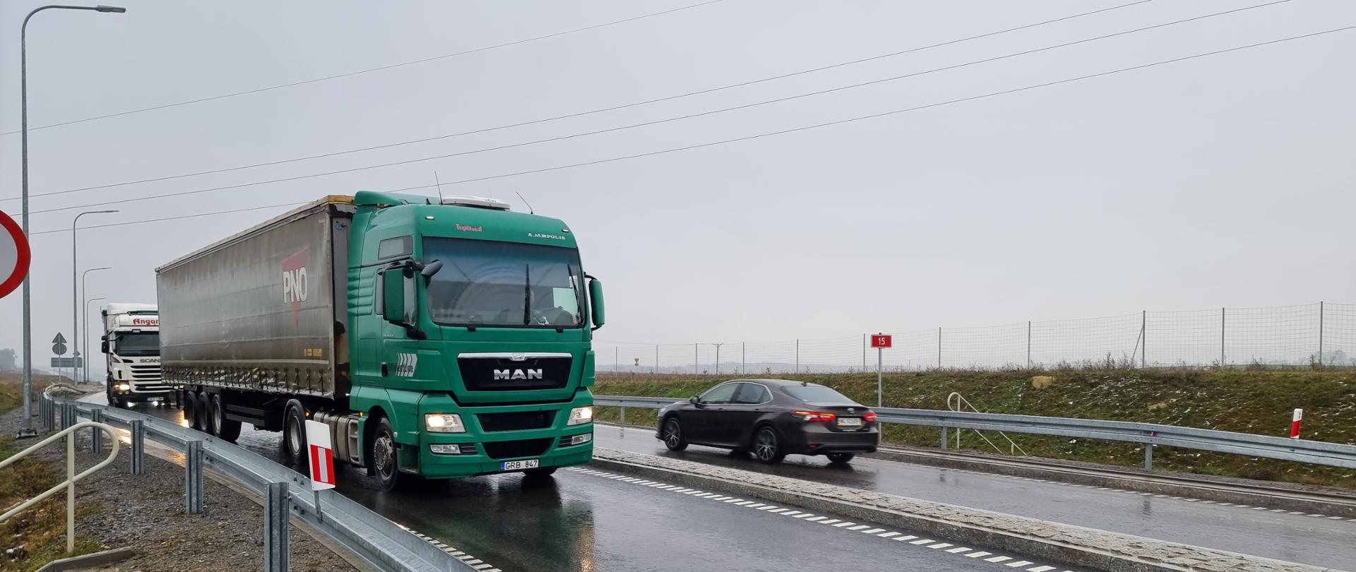 Samochody ciężarowe na asfaltowej drodze w deszczu.
