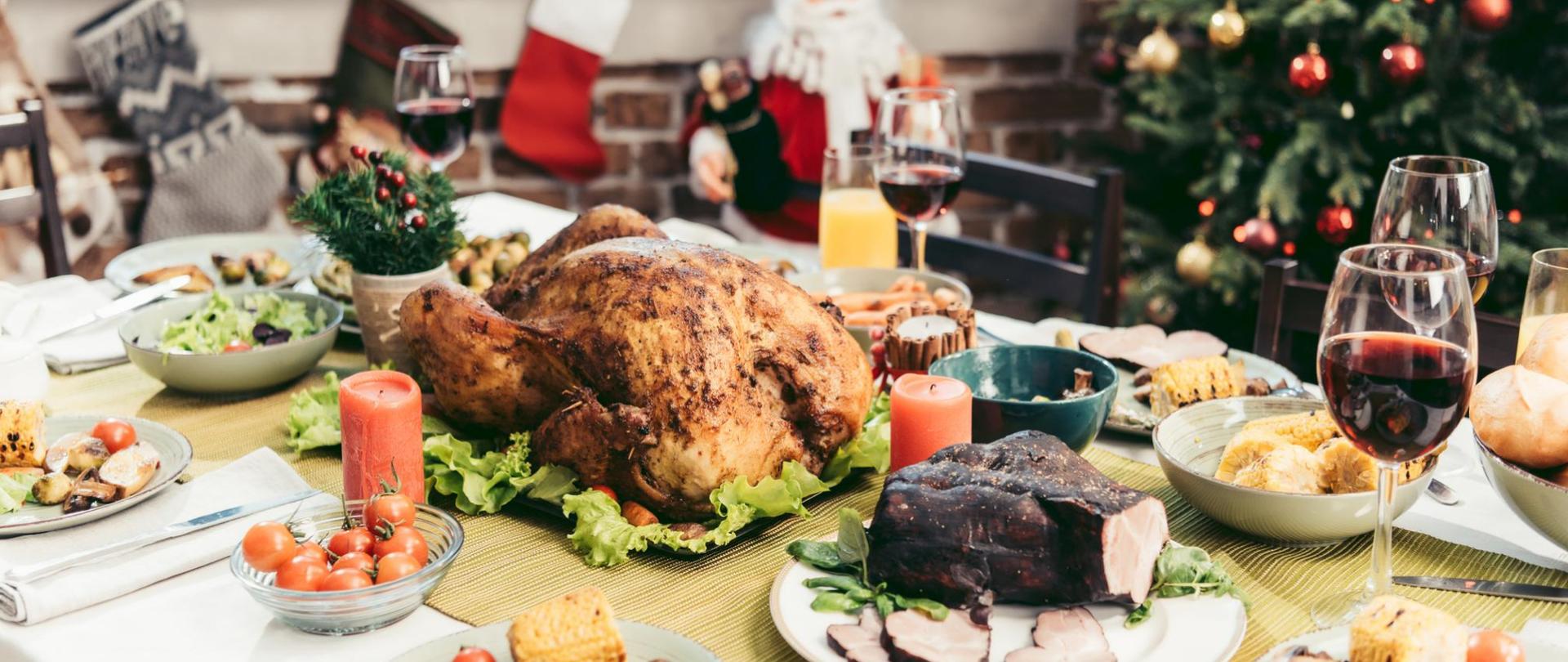 Na zdjęciu jest jedzenie na stole. W tle stoi choinka.