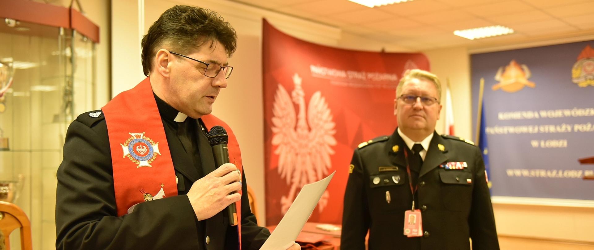 kapelan wojewódzki strażaków czyta modlitwę obok stoi komendant wojewódzki