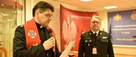 kapelan wojewódzki strażaków czyta modlitwę obok stoi komendant wojewódzki