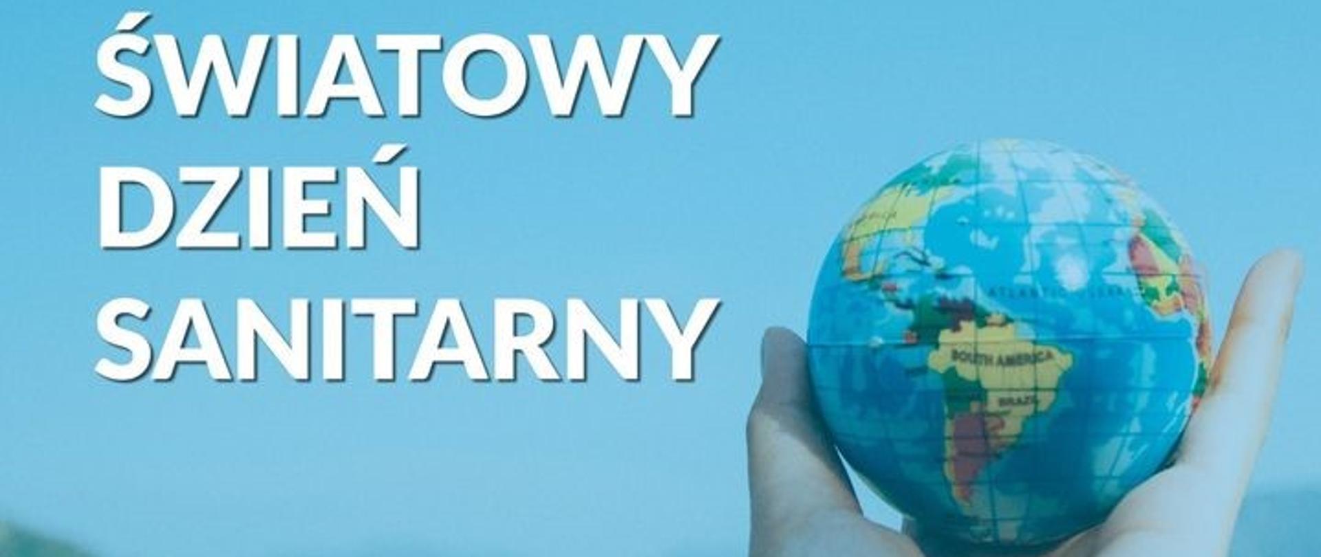 Fotografia ludzkiej dłoni trzymającej globus na rozmytym tle błękitu nieba nad górami. Po lewej stronie napis białą dużą czcionką: 'ŚWIATOWY DZIEŃ SANITARNY'. 