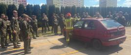 Na zdjeciu widoczni są żołnierze z 103 batalionu lekkiej piechoty wraz z funkcjonariuszem z Komendy Powiatowej Państowej Straży Pożarnej w Ostrowcu Świętokrzyskim podczas zajęć praktycznych i objaśniający rodzaje zagrożeń które mogą być podczas wypadków komunikacyjnych.