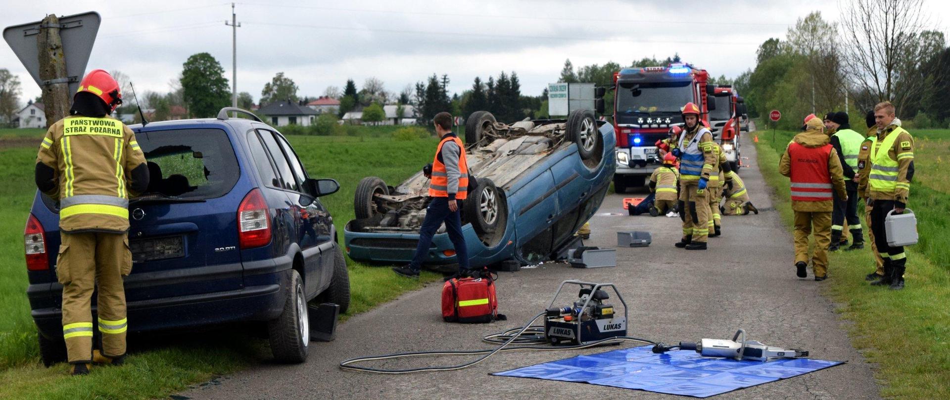 Zdjęcie zrobione na zewnątrz podczas wojewódzkich ćwiczeń strażaków. Strażacy ochotniczych straży pożarnych oraz Państwowej Straży Pożarnej realizują założone ćwiczenia.