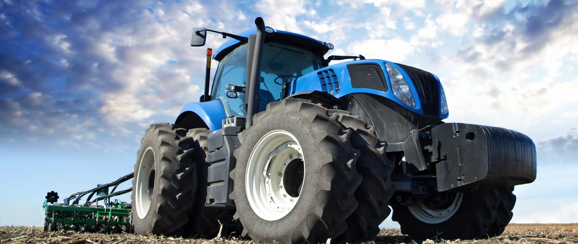 The tractor wheels on the huge field, a farmer riding a tractor, a tractor working in a field agricultural machinery in the work, tractor in the background cloudy sky