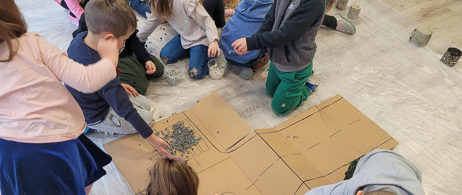 Przedszkolaki poprzez zabawę zapoznają się z materiałami do budowy dróg: próbki gruntu, kruszyw, betonu i asfaltu.