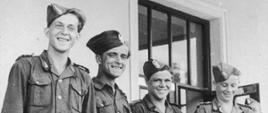 Czterech młodych mężczyzn w mundurach junackich, na głowach mają zawadiacko ubrane furażerki (czapki wojskowe). Mężczyźni uśmiechają się. 