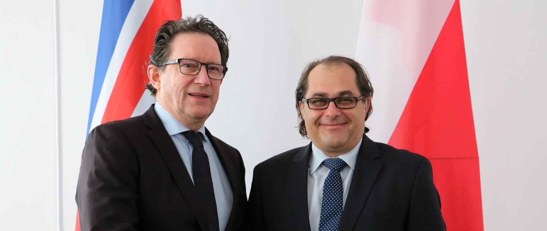 Na zdjęciu od lewej: minister Islandii Kristján Þór Júlíusson i minister Marek Gróbarczyk pozują do zdjęcia w geście powitania. W tle flaga Polski i Islandii.