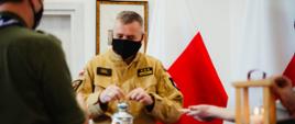 Pomorski komendant wojewódzki Państwowej Straży Pożarnej trzyma przekazane przez harcerzy Betlejemskie Światełko Pokoju.