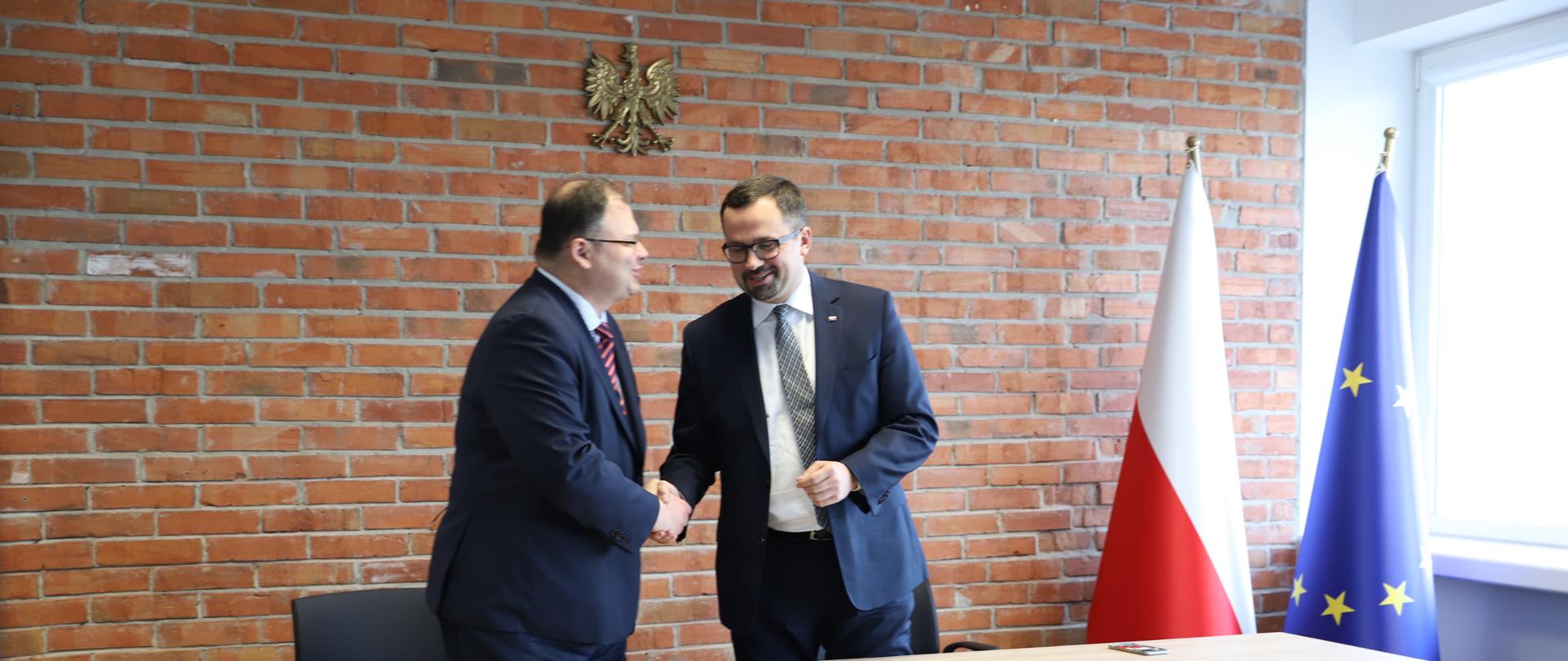 Panowie ubrani w garnitur uściskują sobie dłonie.