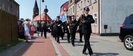 Przemarsz kolumny strażaków w mundurach galowych