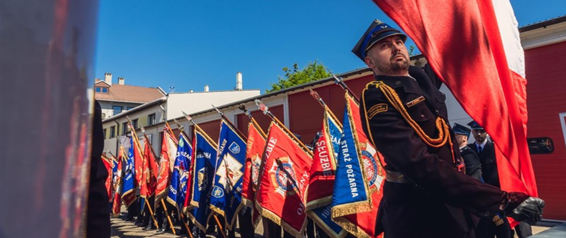 Podniesienie flagi państwowej, w tle poczty sztandarowe OSP z powiatu tarnogórskiego
