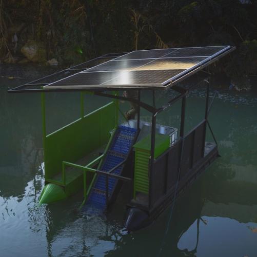Mała łódka na rzece z widocznymi panelami słonecznymi, która służy jako oczyszczalnia wody