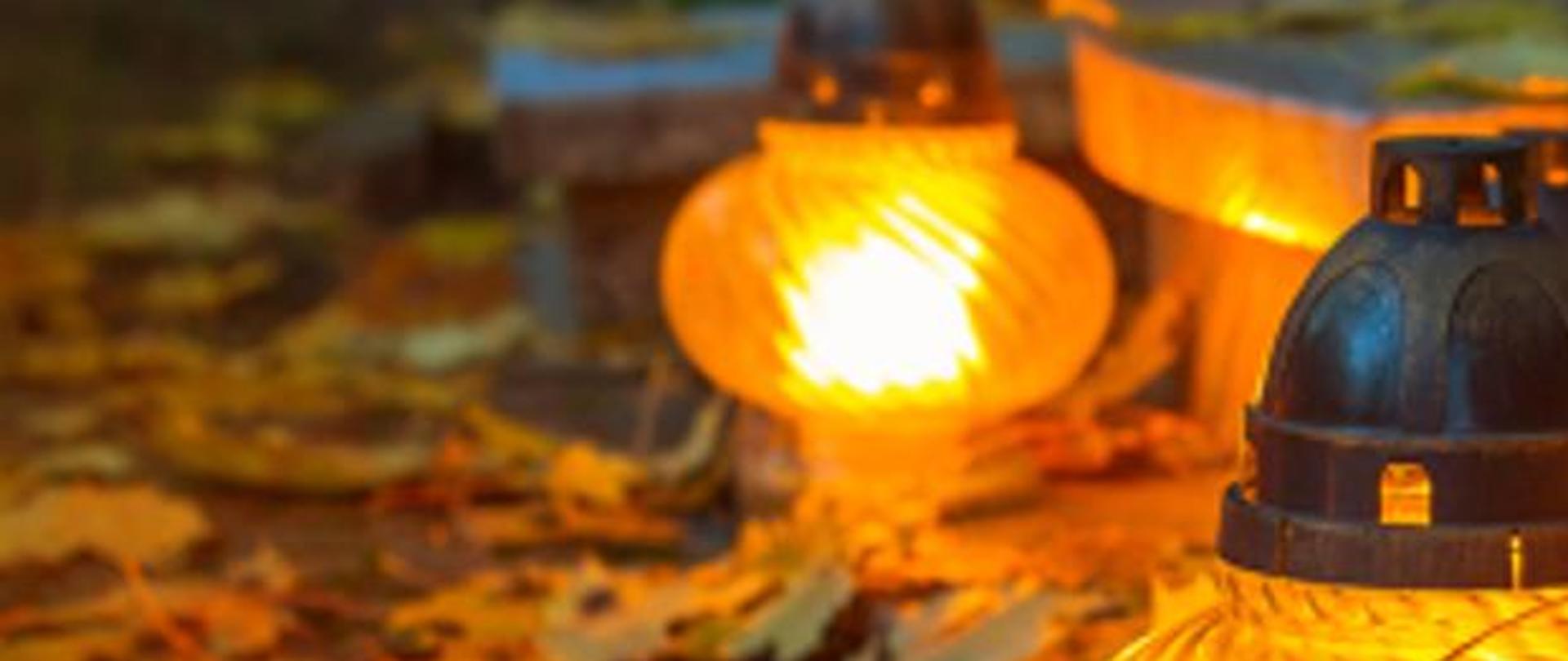 na zdjęciu widać zapalony znicz stojący obok nagrobka