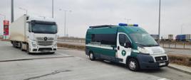 Kontrola zespołu pojazdów zatrzymanego przez inspektorów podlaskiej ITD na S61. Po lewej zatrzymana ciężarówka, a po prawej inspekcyjny furgon na przydrożnym parkingu. W oddali po lewej stacja paliw, a po prawej ruch ciężarówek.