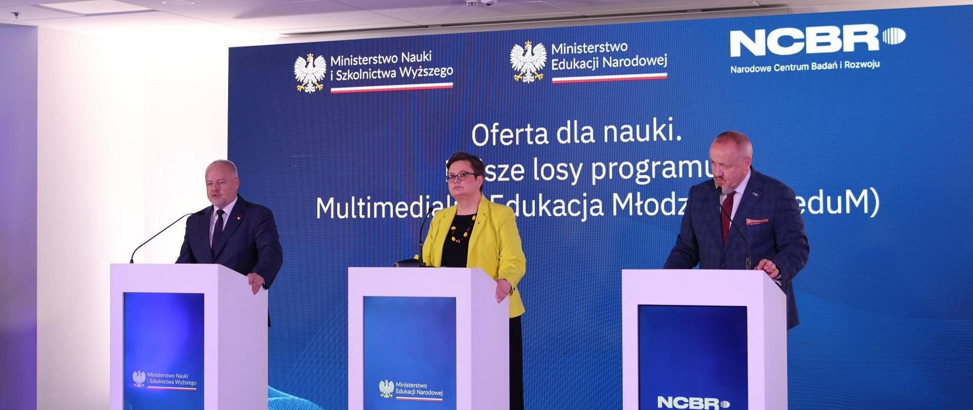 Za trzema mównicami stoją wiceminister Gzik, wiceminister Lubnauer i dyrektor NCBR, za nimi granatowa ścianka z napisem Oferta dla nauki.