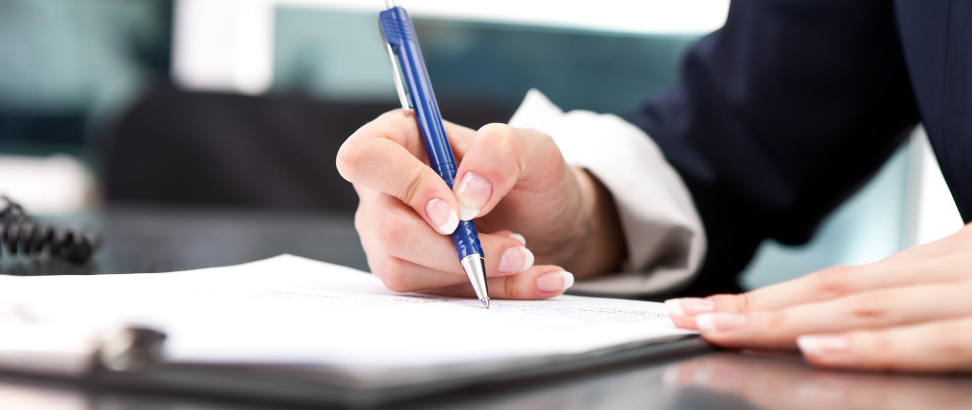 woman's hand with pen signing document, close up