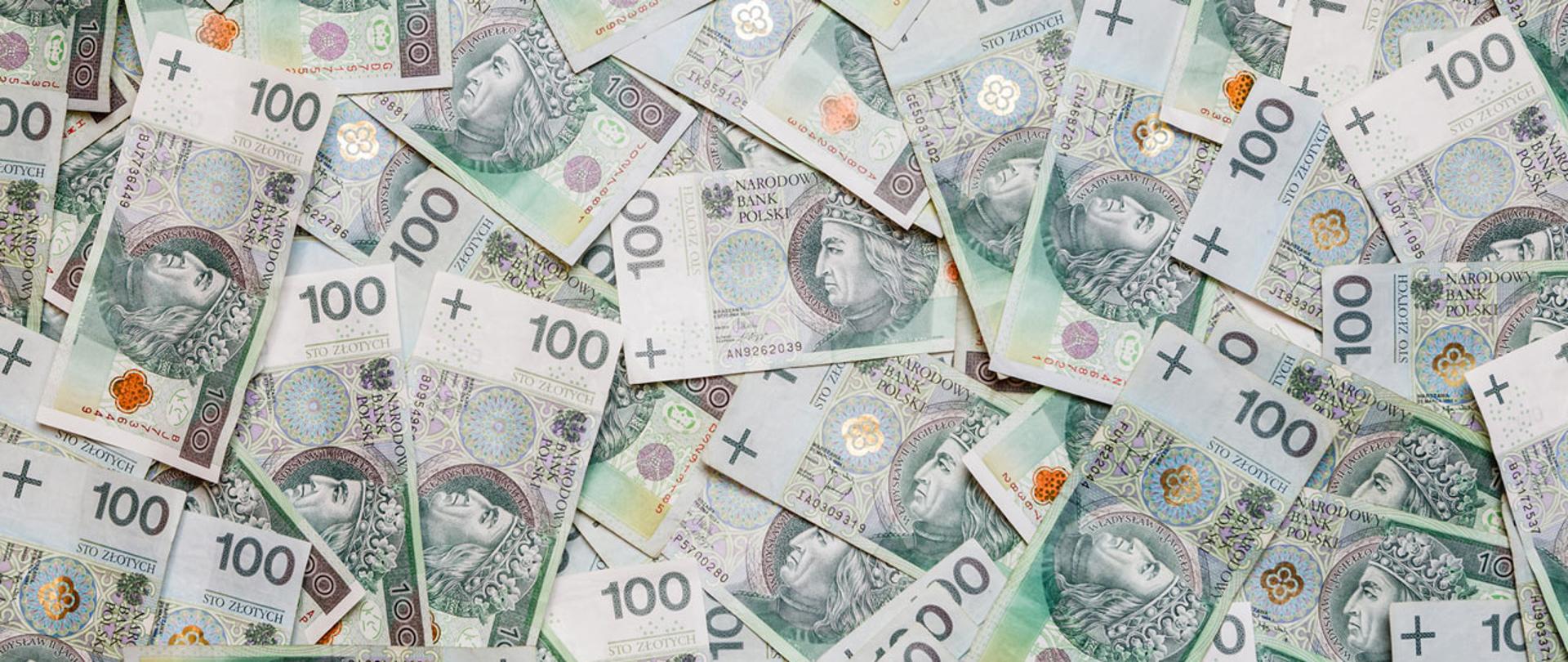 Zdjęcie poglądowe z rozrzuconymi banknotami o nominale 100 zł.
