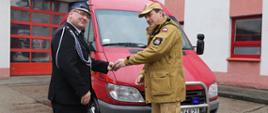 Komendant Centralnej Szkoły PSP wręcza kluczyki do przekazywanego samochodu druhowi OSP, w tle przekazywany samochód Mercedes Sprinter