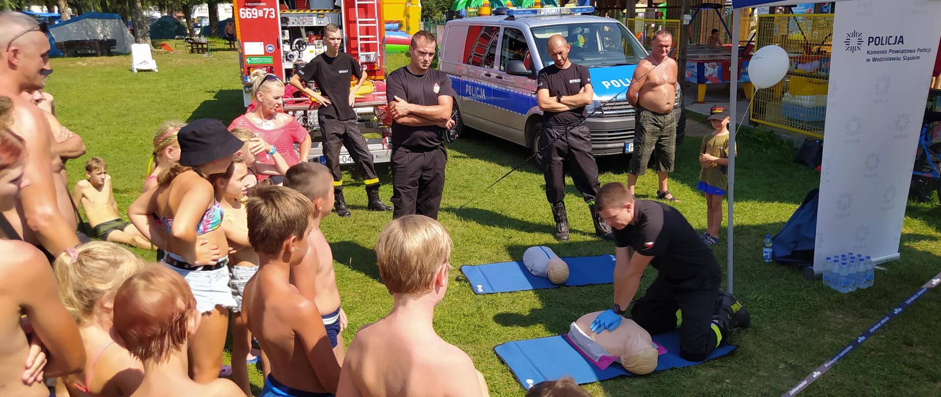Na zdjęciu strażacy prowadzą pokazy udzielania pierwszej pomocy na fantomach dla odpoczywających na plaży osób