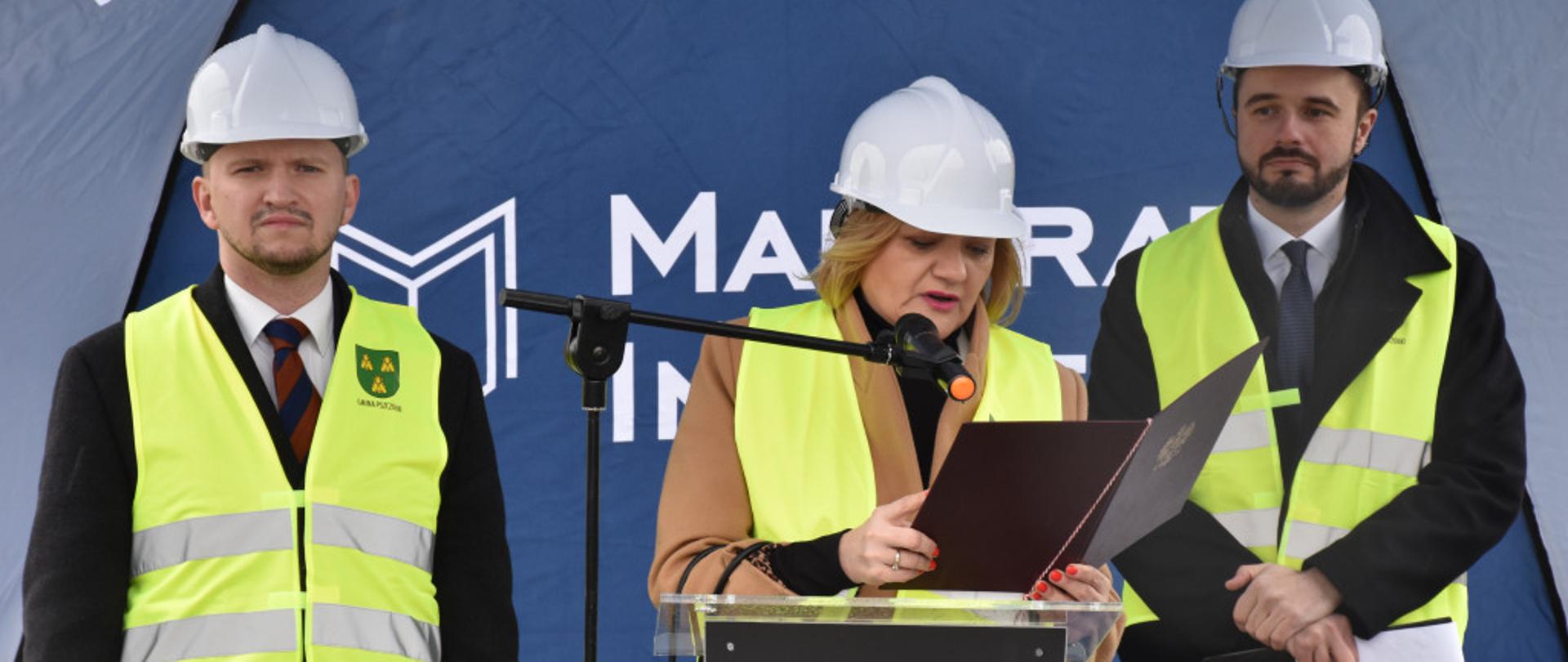 Kobieta stoi za mównicą i czyta