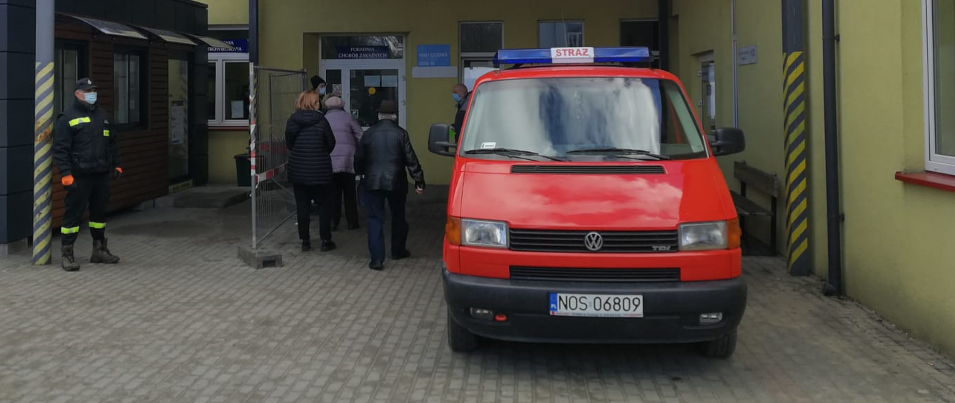 Strażacki samochód typu bus ustawiony przed wejściem do szpitala zakaźnego w Ostródzie. 