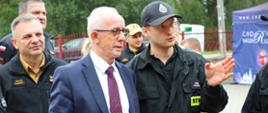 Wizyta Wiceministra Spraw Wewnętrznych i Administracji oraz kadry PSP u druhów ochotników - wiceminister i strażacy PSP podczas rozmowy , w tle strażacy PSP