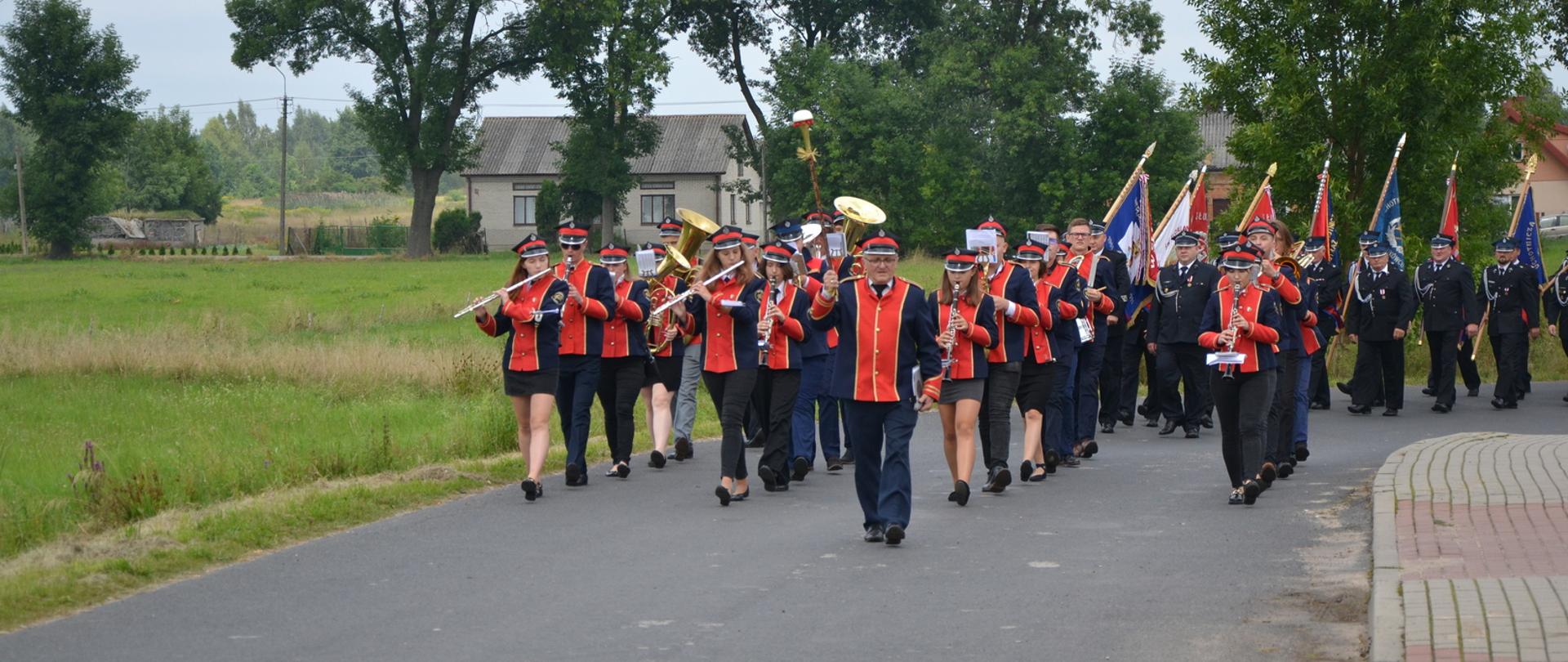 Przemarsz strażaków oraz zebranych gości do strażnicy OSP pod przewodnictwem Orkiestry Dętej z Dobrego