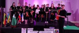 Grupa uczniów orkiestry PSM I st. w Kłodzku pozujących do zdjęcia grupowego trzymająca instrumenty, orkiestry PSM I st. w Kłodzku, która brała udział w konkursie Międzynarodowe Konfrontacje Muzyki Klasycznej - 19 czerwca 2023 r.